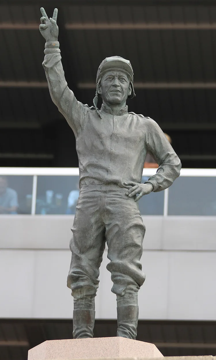 Bronze statue of jockey Avelino Gomez at Woodbine Racetrack, arm raised in a victory salute